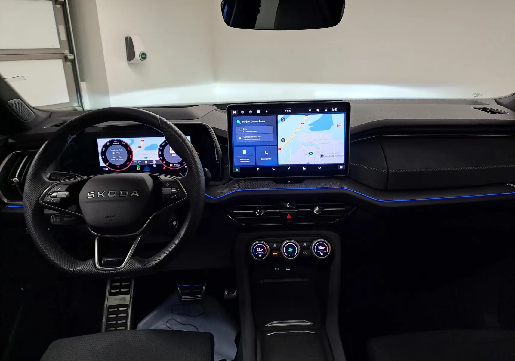 Vue intérieure frontale du tableau de bord du Skoda Kodiaq 2025 avec écran tactile central et éclairage d'ambiance bleu.