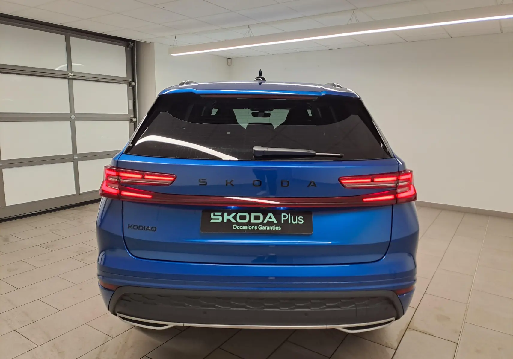 Vue arrière d'un Skoda Kodiaq Bleu RS 2025 avec feux LED allumés dans un garage intérieur.