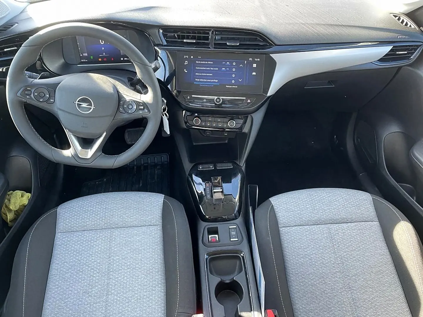 Vue intérieure avant de l’Opel Corsa 2025, tableau de bord noir avec écran tactile et sièges tissu gris clair et noir.