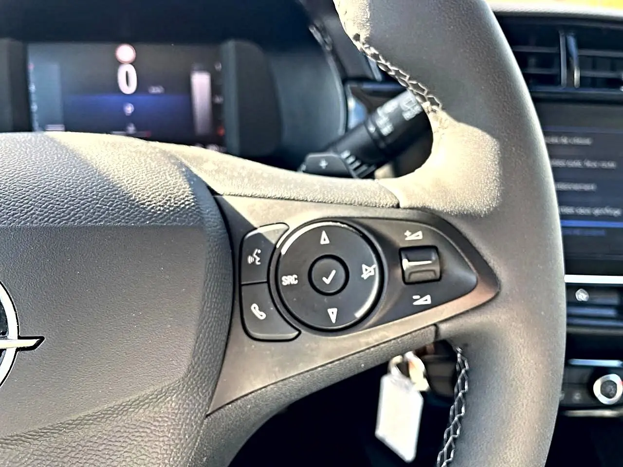 Gros plan sur le volant multifonction noir de l'Opel Corsa 1.2 turbo 100 edition, avec commandes audio visibles.