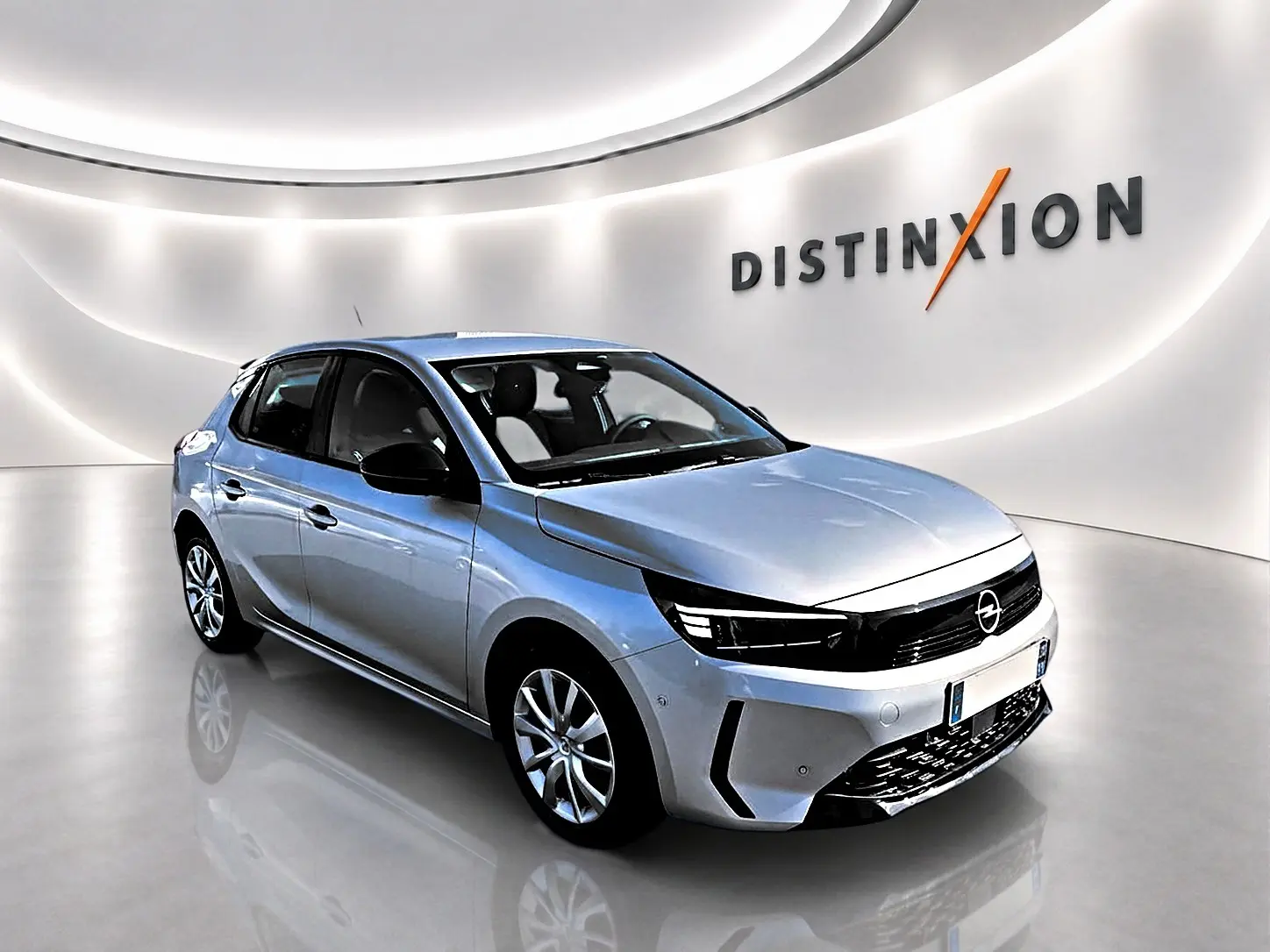 Opel Corsa gris vue 3/4 avant droit dans un showroom lumineux avec logo Distinxion en arrière-plan.