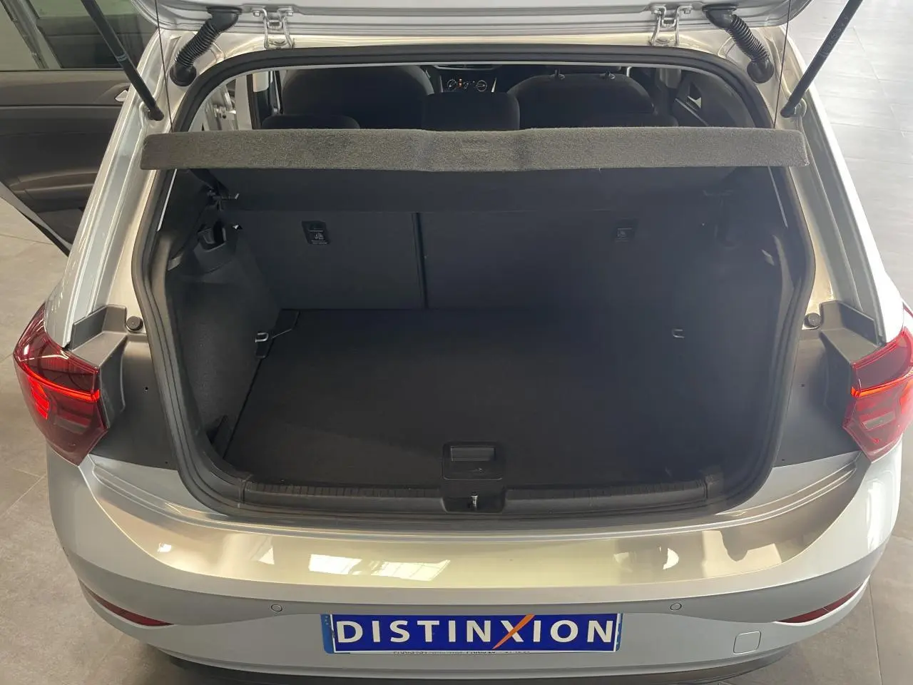 Coffre ouvert vu de l'arrière d'une Volkswagen Polo gris clair 2024 avec hayon et feux arrière LED visibles.
