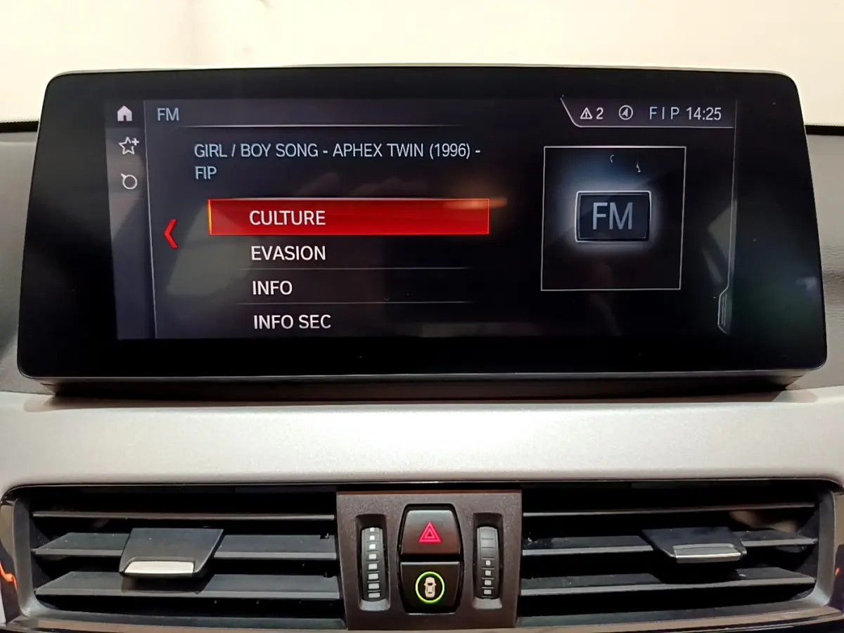 Écran central multimédia affichant la radio FM avec menu de sélection dans l’habitacle d’une BMW X1 sDrive18i Lounge 2019.