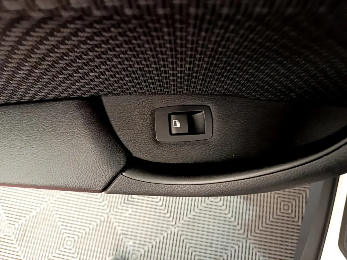 Bouton de verrouillage de porte sur la garniture intérieure noire côté gauche d’un BMW X1 blanc sDrive18i Lounge.