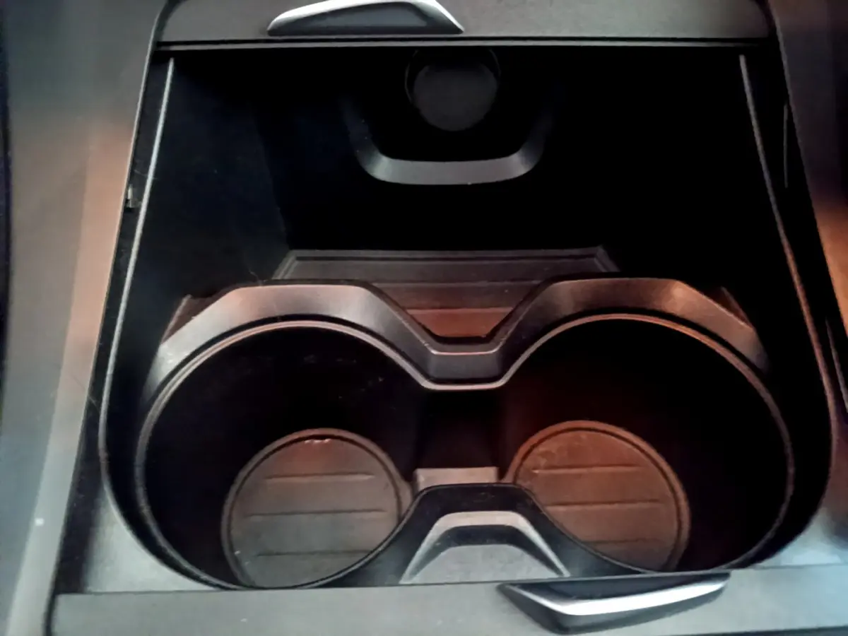 Gros plan sur les porte-gobelets noirs au centre de la console intérieure du BMW X1 sDrive18i Lounge blanc.