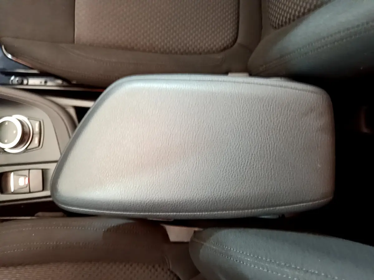 Vue rapprochée de l'accoudoir central en cuir noir et des sièges tissu marron à l'intérieur d'un BMW X1 sDrive18i Lounge.