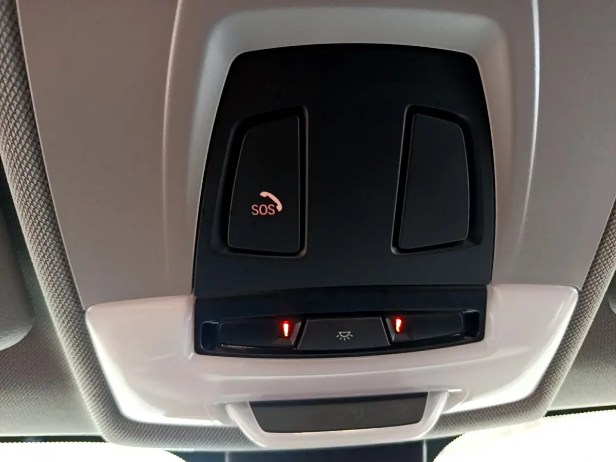Gros plan sur les commandes de plafonnier et bouton SOS du toit intérieur du BMW X1 sDrive18i blanc de 2019.