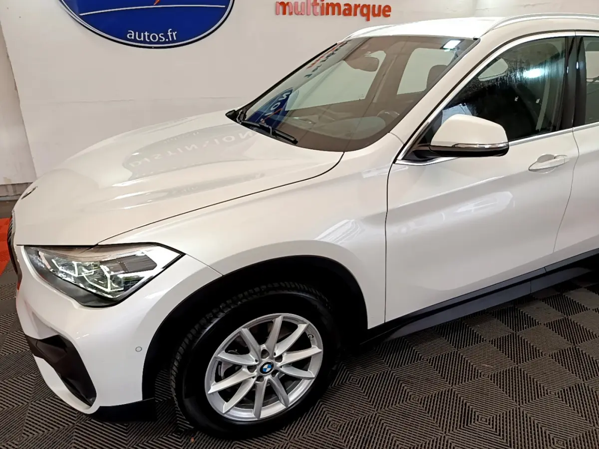 Vue 3/4 avant droit d'un BMW X1 sDrive18i Lounge blanc avec jantes alliage et rétroviseurs blancs.