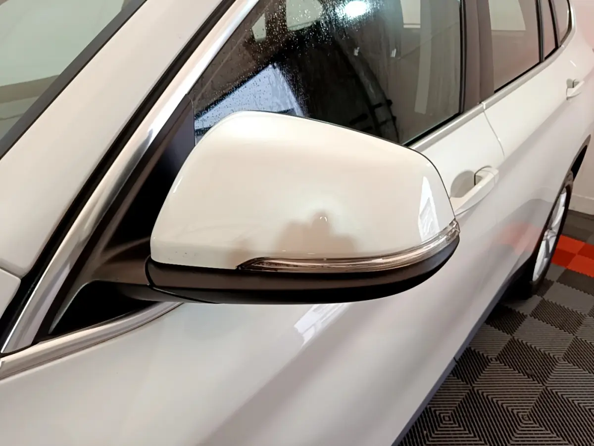 Gros plan sur le rétroviseur droit blanc du BMW X1 sDrive18i Lounge 2019, avec carrosserie blanche visible en arrière-plan.
