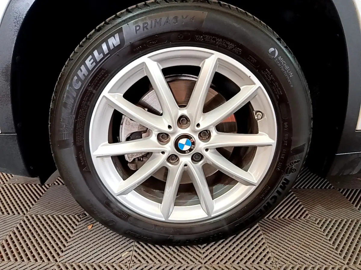 Gros plan sur la roue avant droite d’un BMW X1 blanc, avec jante alliage et pneu Michelin Primacy 4.