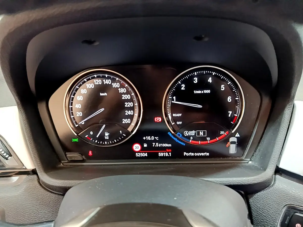 Vue rapprochée du tableau de bord numérique de la BMW X1 sDrive18i Lounge 2019 affichant vitesse et compte-tours.