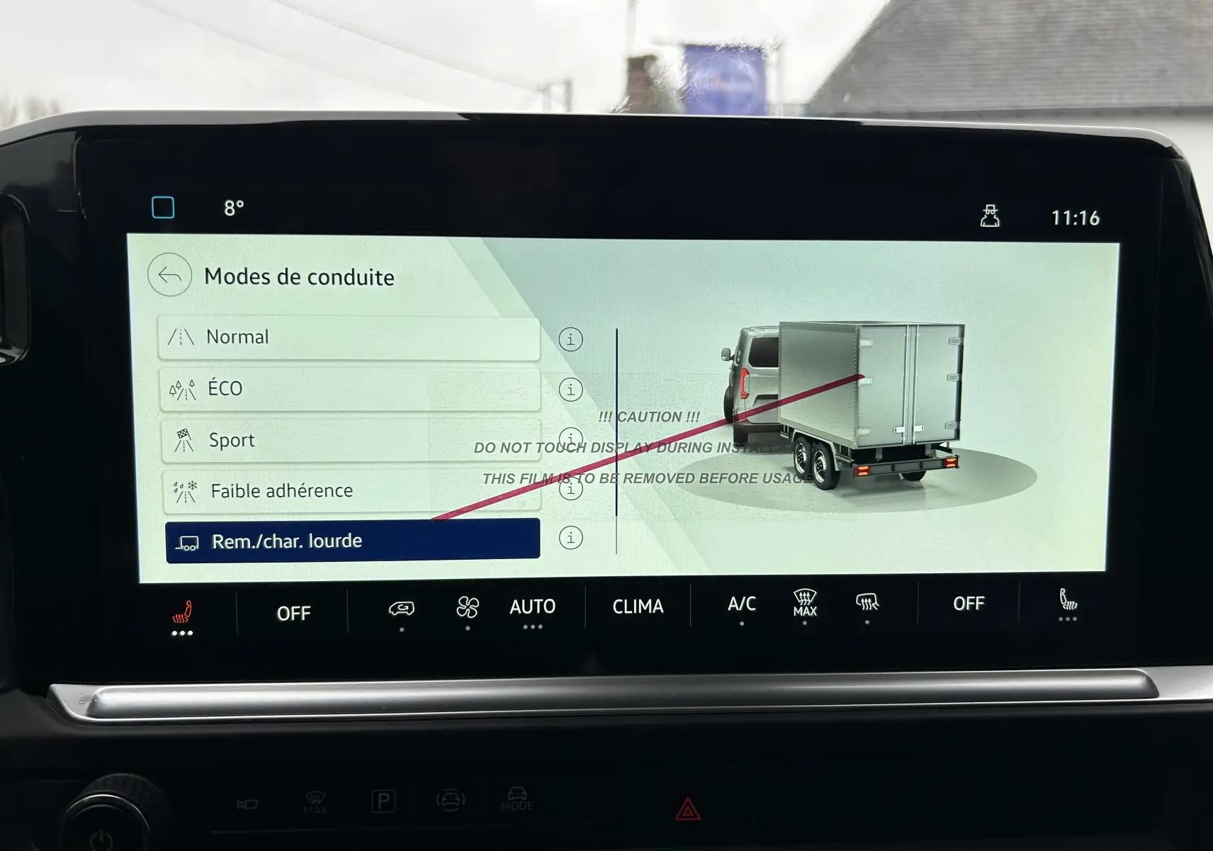 Écran tactile intérieur du Volkswagen Transporter T7 affichant les modes de conduite, avec illustration d’un utilitaire gris en vue arrière.