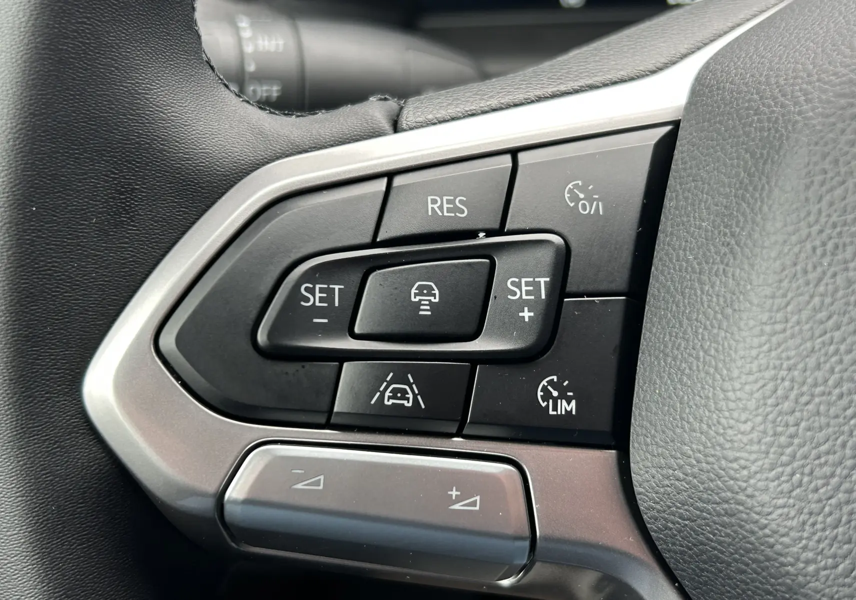 Gros plan sur les commandes de régulateur de vitesse au volant en cuir noir du Volkswagen Transporter T7 Business.