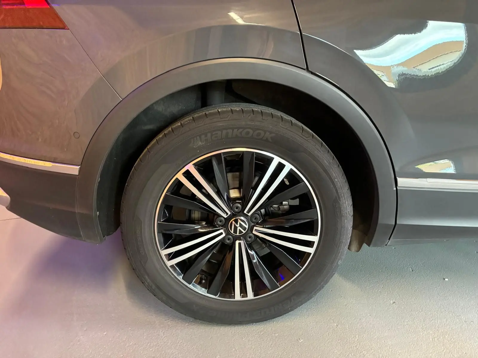 Gros plan sur la roue arrière droite du Volkswagen Tiguan gris 2023 avec jante alliage noire et argent.