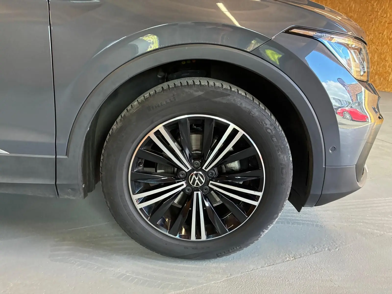 Gros plan sur la roue avant droite d’un Volkswagen Tiguan gris, mettant en valeur la jante noire et argentée.