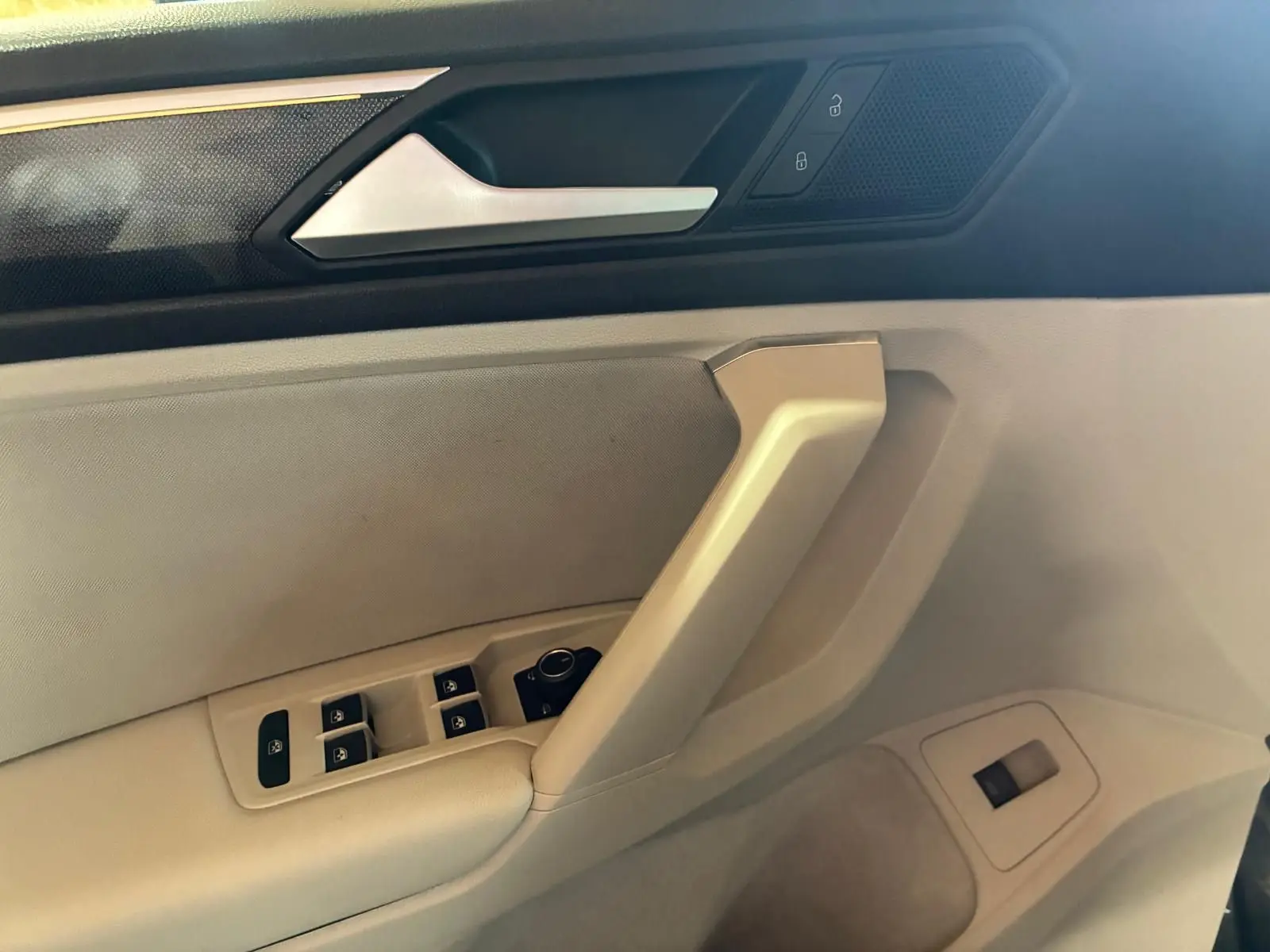 Détail de la porte côté conducteur du Volkswagen Tiguan 2023, avec commandes électriques et finition beige.