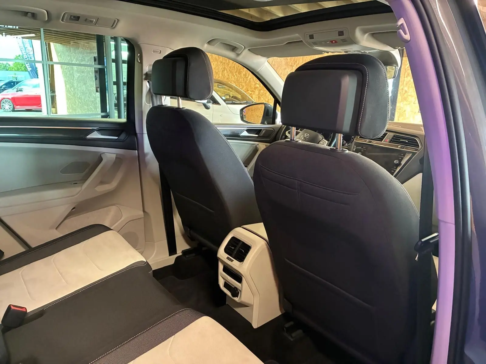 Vue intérieure arrière du Volkswagen Tiguan 2023, sièges bicolores noirs et beige avec toit ouvrant panoramique visible.
