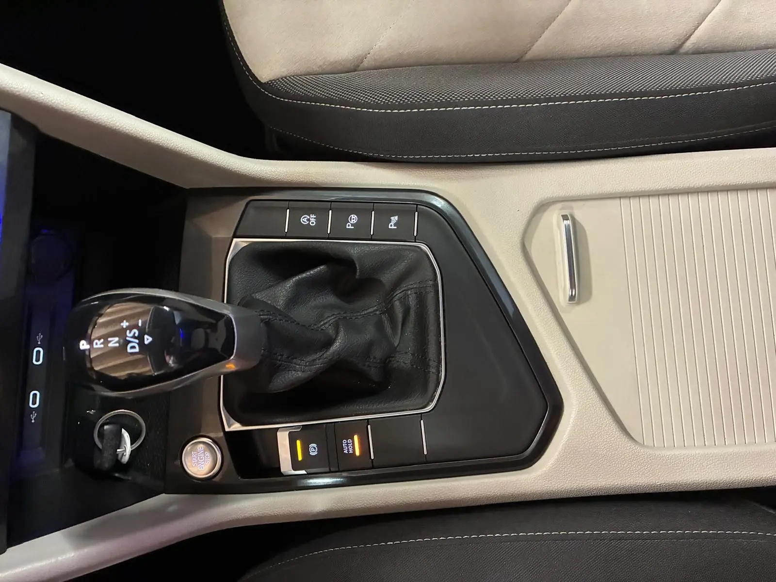 Vue rapprochée de la console centrale beige et noire du Volkswagen Tiguan 2023 avec levier de boîte auto et bouton start/stop.