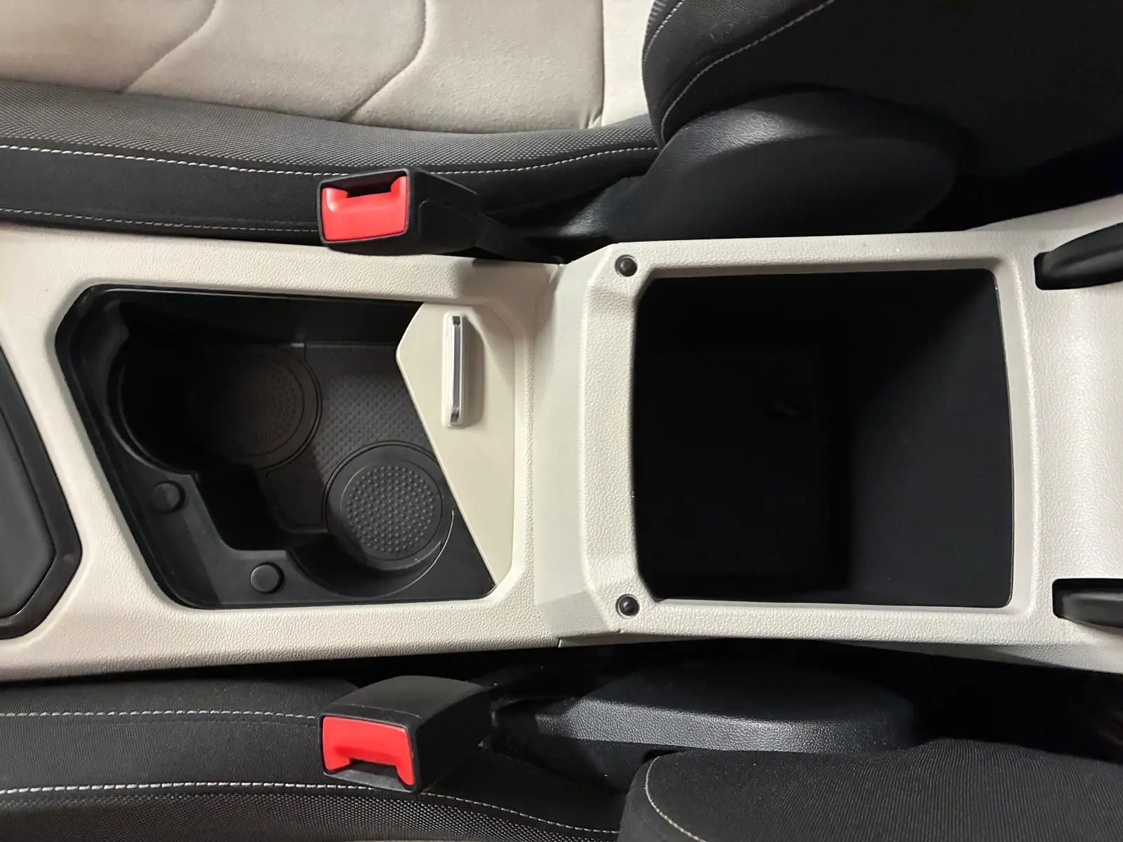 Vue plongeante sur la console centrale beige et noire du Volkswagen Tiguan 2.0 TDI 150 Elegance avec porte-gobelets et accoudoirs.