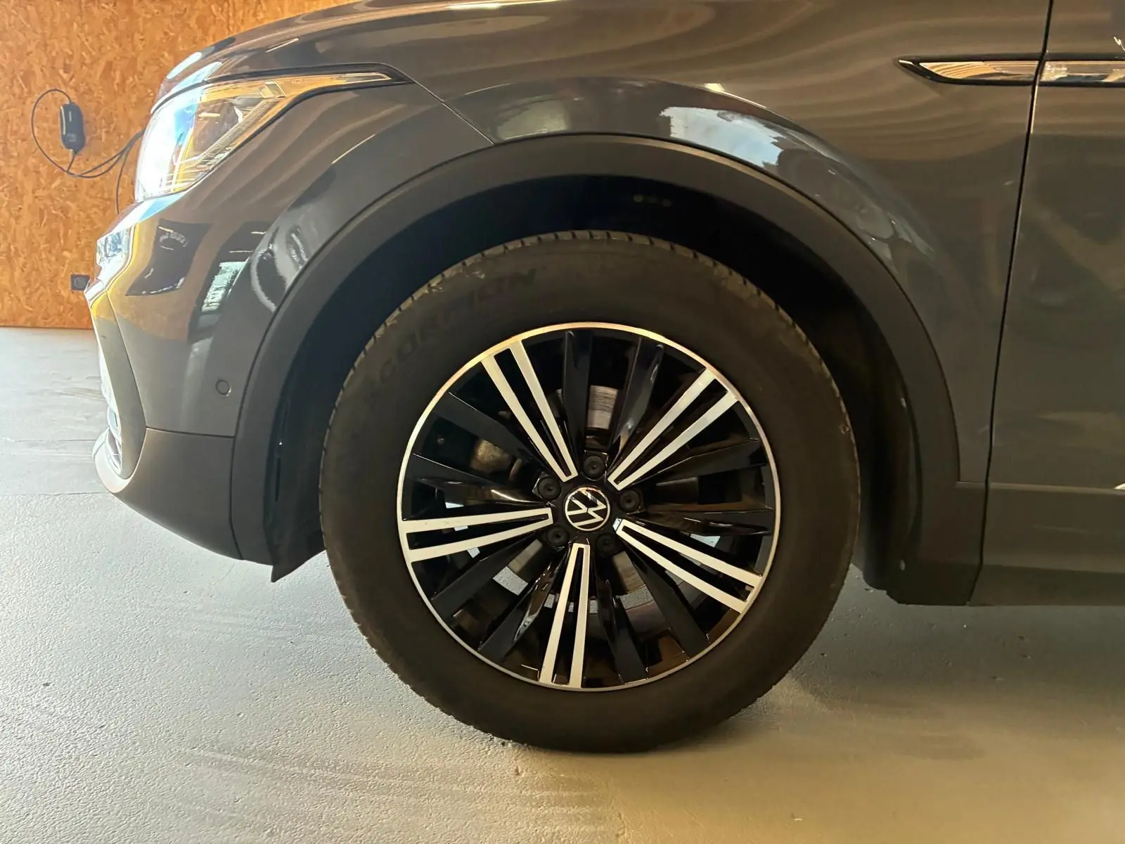 Gros plan sur la roue avant gauche du Volkswagen Tiguan gris 2023 avec jante alliage noire et argentée.