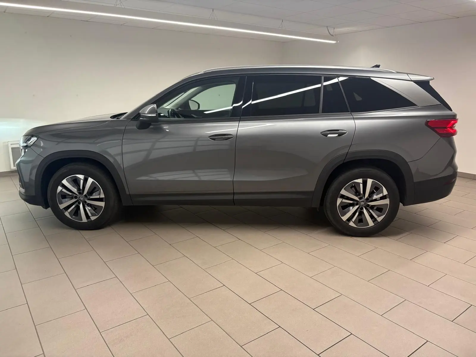 Vue de profil côté gauche du Skoda Kodiaq 2025 gris graphite avec jantes alliage et vitres teintées.
