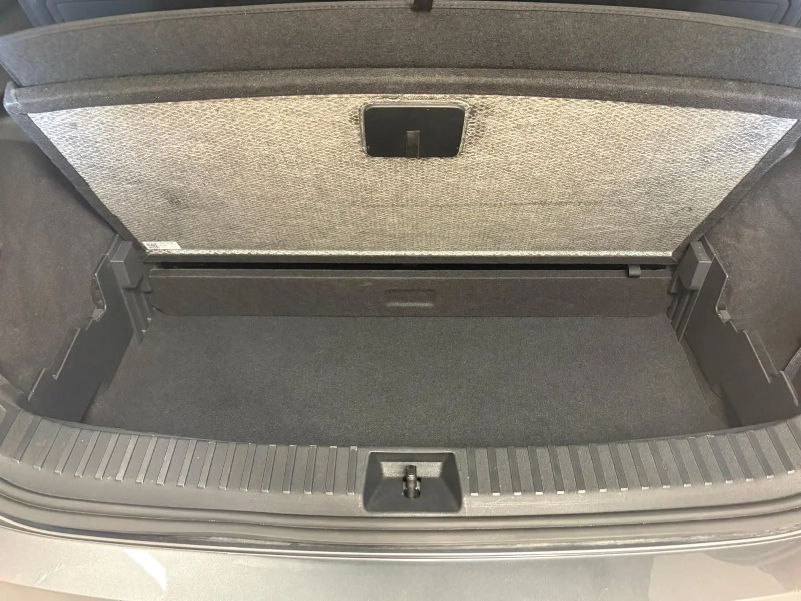 Coffre ouvert d’un Skoda Kodiaq gris graphite 2025, vue plongeante sur l’espace de rangement vide.