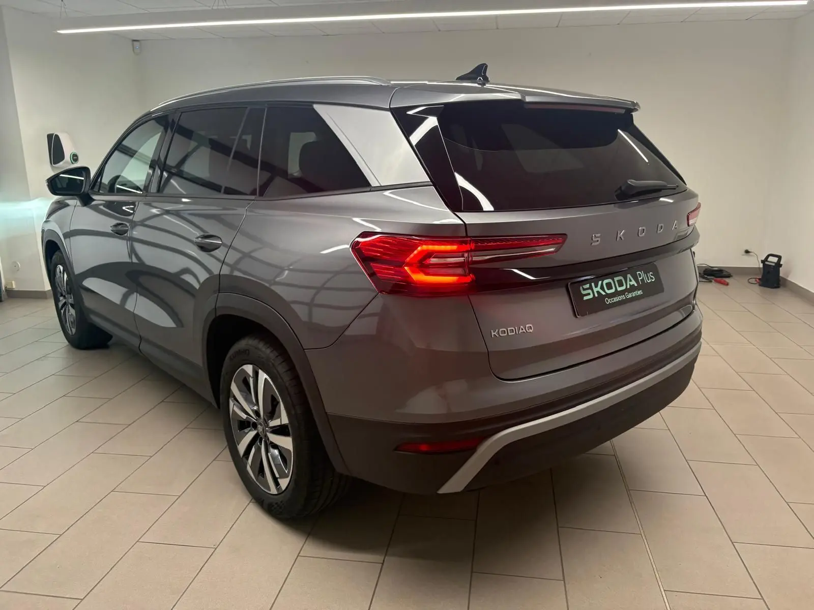 Vue 3/4 arrière droite du Skoda Kodiaq gris graphite 2025 avec feux arrière allumés et jantes alliage.