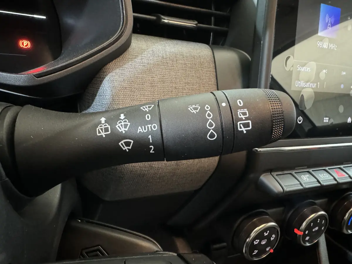 Gros plan sur la commande des essuie-glaces à gauche du volant dans l'habitacle de la Renault Clio gris clair 2025.