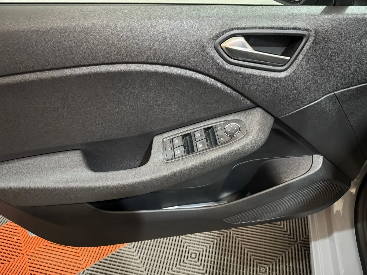 Vue rapprochée de la porte avant gauche grise de la Renault Clio 2025 avec commandes électriques des vitres et poignée argentée.