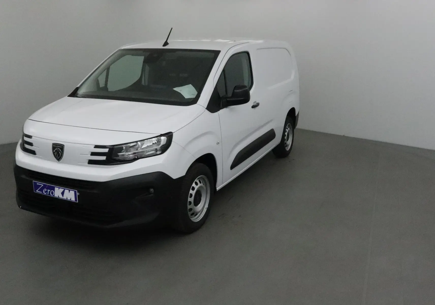 Peugeot Partner blanc en 3/4 avant droit, utilitaire compact avec calandre noire et jantes acier simples.