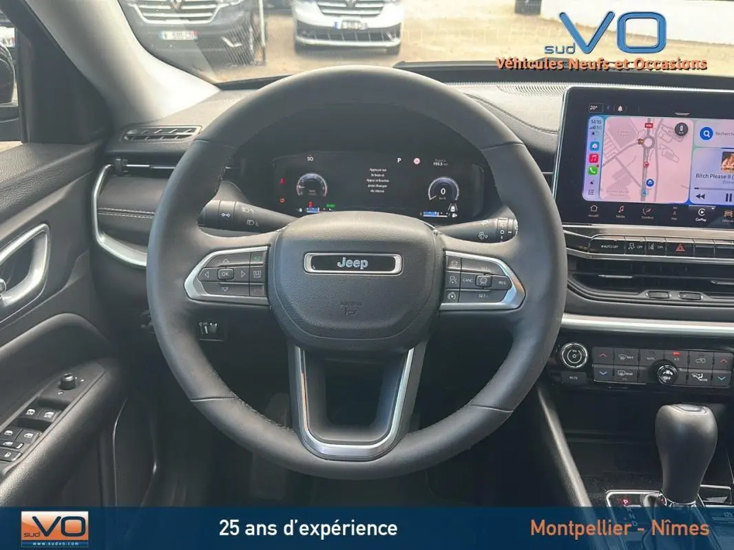 Vue intérieure centrée sur le volant Jeep Compass 2023 avec tableau de bord numérique et écran tactile multimédia.