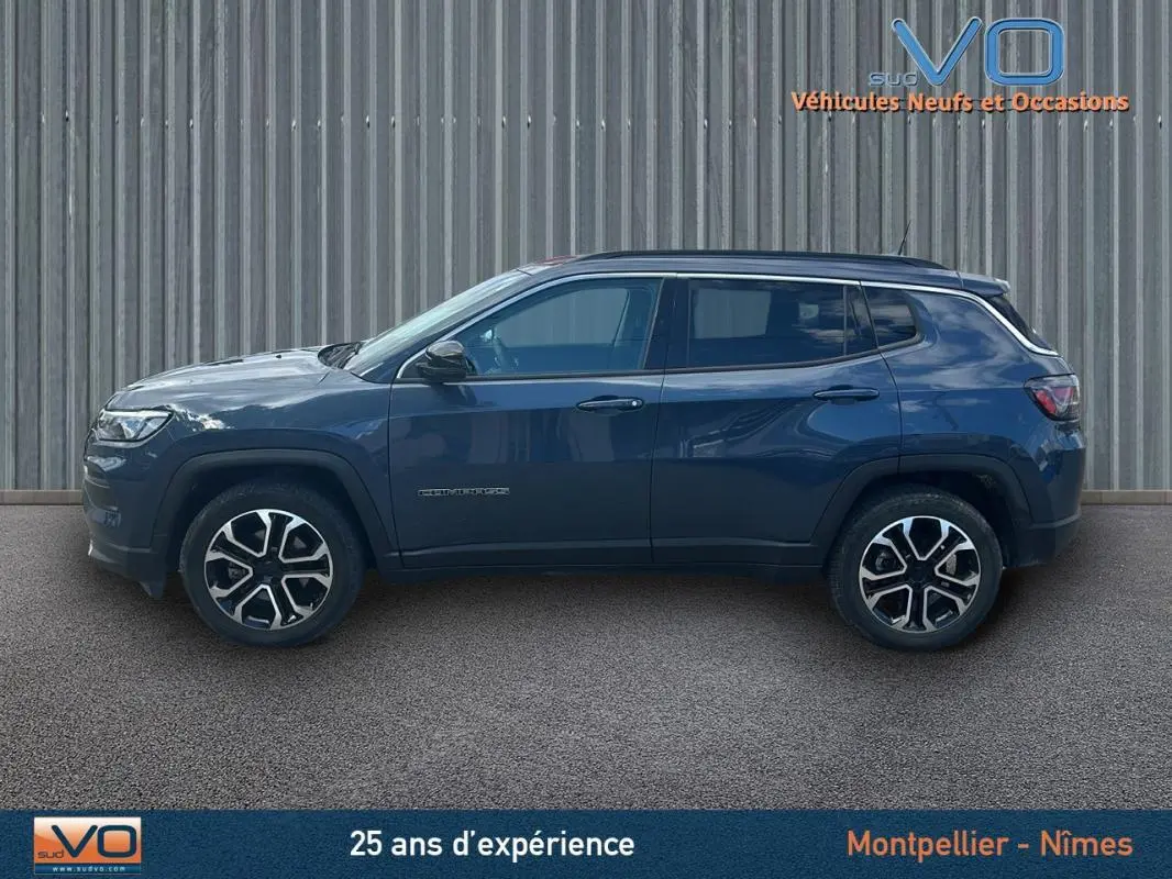 Vue latérale droite d'un Jeep Compass bleu 2023 avec jantes 18 pouces et barres de toit, sur fond neutre.