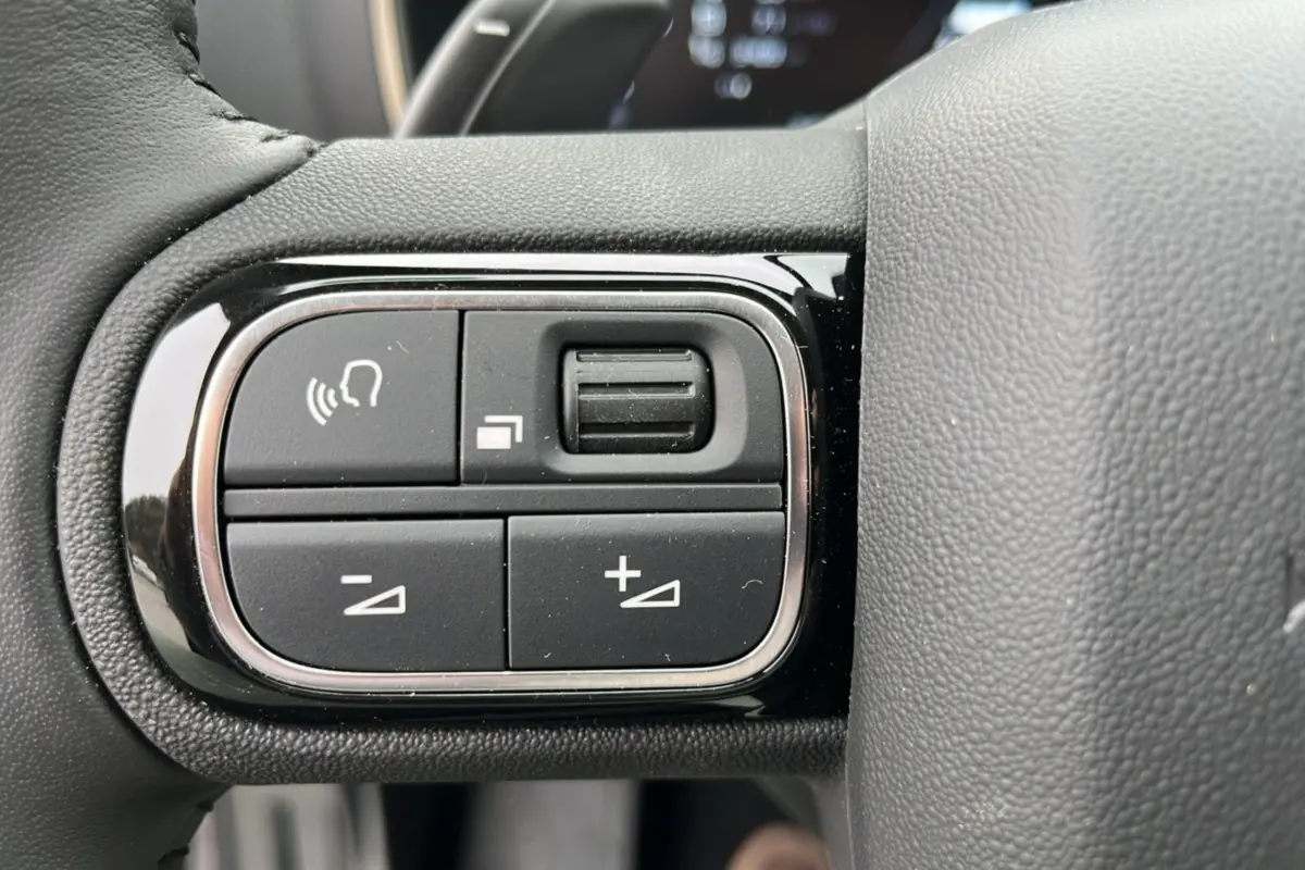 Gros plan sur les commandes noires du volant cuir multifonctions du Citroën C5 Aircross Hybrid 145, finition Eclipse Blue.