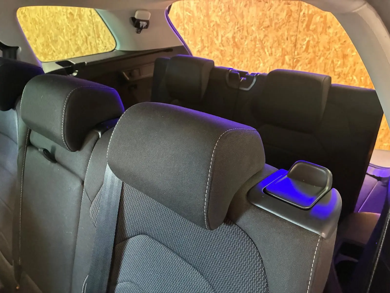 Vue rapprochée des sièges arrière noirs en tissu du Skoda Kodiaq 7 places, avec appuie-têtes et ceintures visibles.