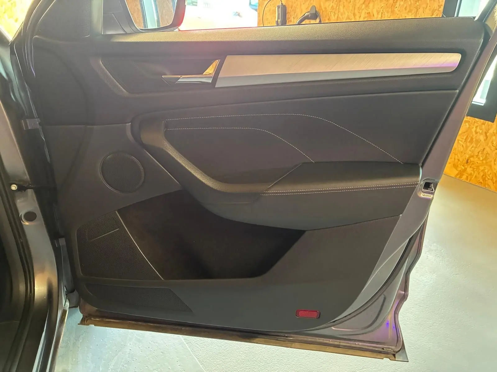 Vue intérieure côté gauche de la porte arrière grise du Skoda Kodiaq 2023 avec insert aluminium brossé et haut-parleur intégré.