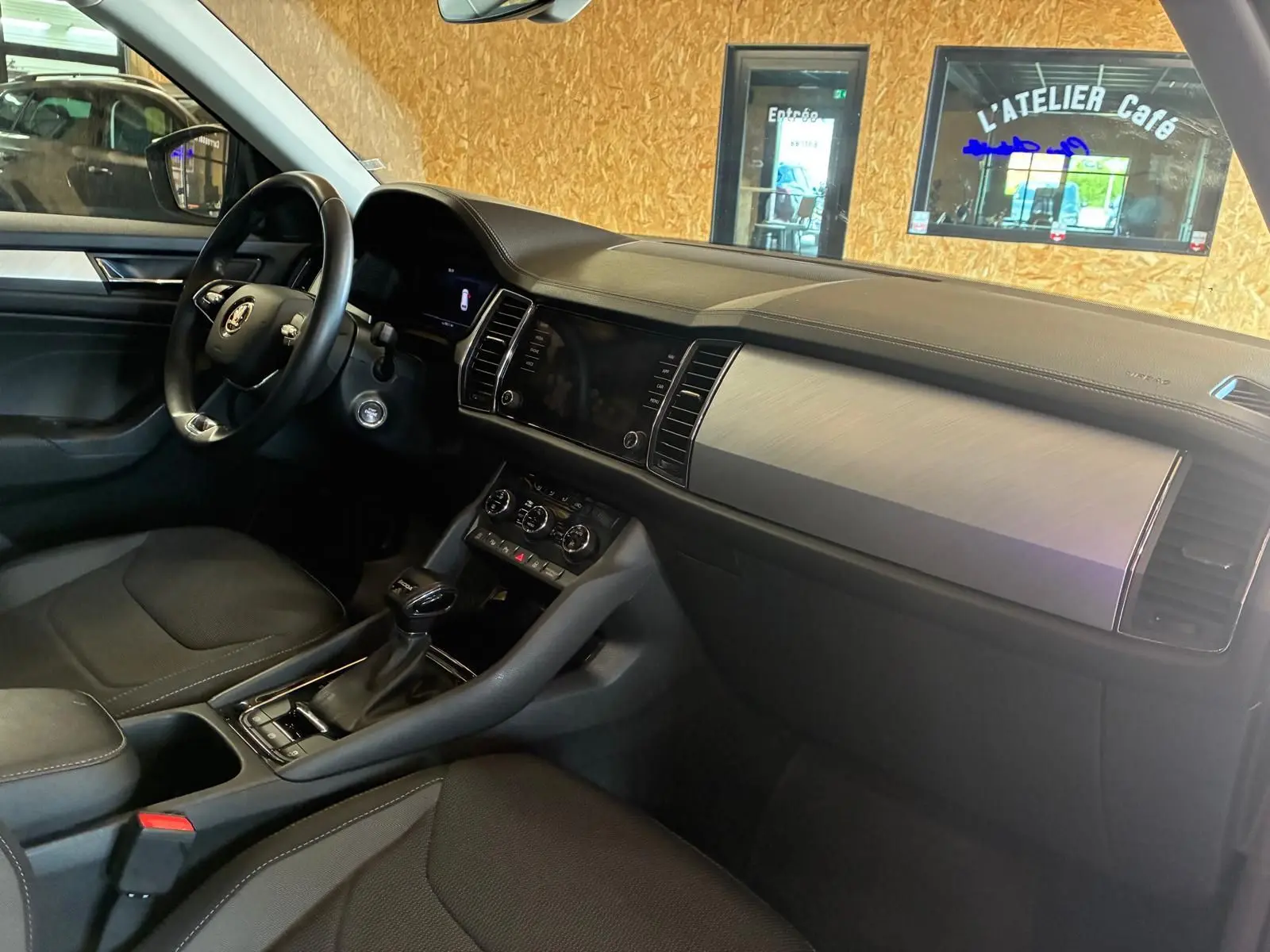 Vue intérieure côté conducteur du Skoda Kodiaq gris 2023, tableau de bord avec inserts aluminium et console centrale noire.