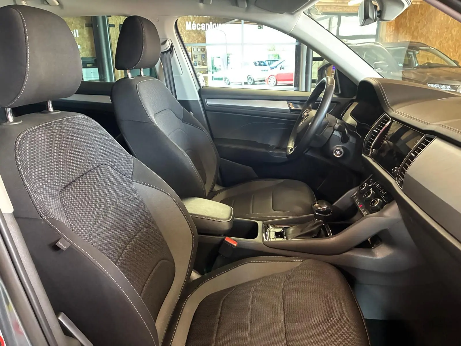 Vue intérieure côté droit du Skoda Kodiaq 2023, montrant les sièges tissu noirs et la console centrale avec levier de vitesses.