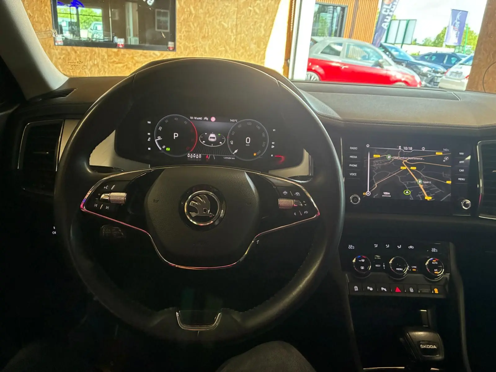Vue intérieure centrée sur le volant noir et le tableau de bord digital du Skoda Kodiaq 2023 avec écran GPS allumé.