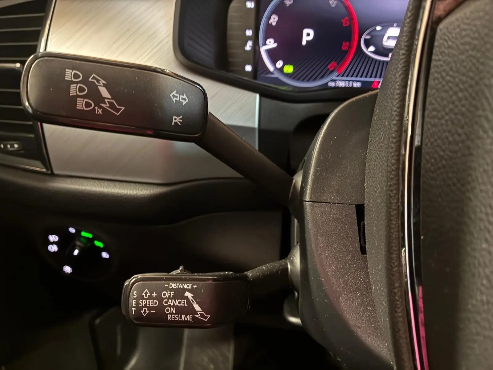 Gros plan sur les commandes au volant d’un Skoda Kodiaq gris, avec tableau de bord numérique en arrière-plan.