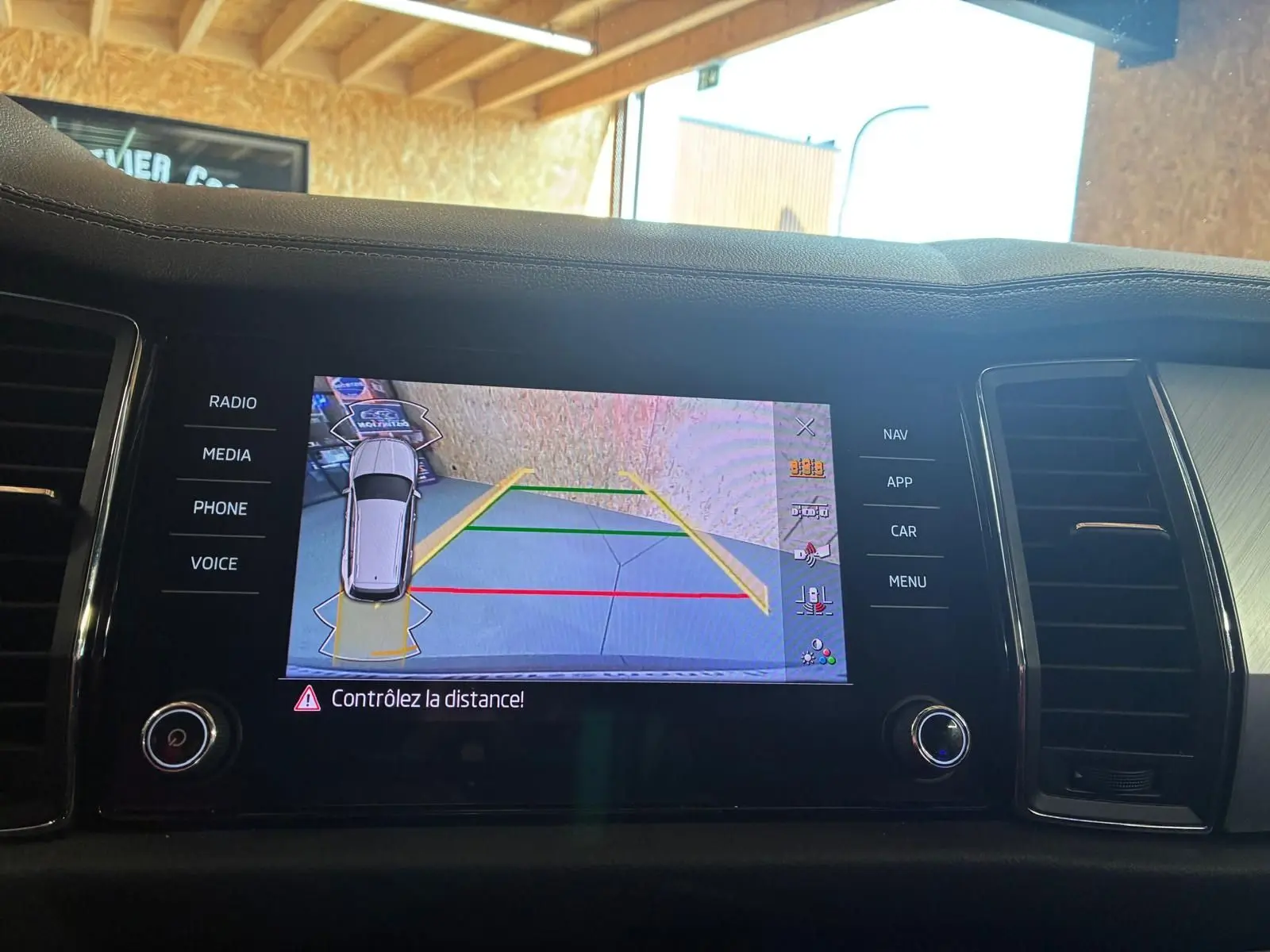 Écran central du tableau de bord montrant la caméra de recul et l’aide au stationnement du Skoda Kodiaq gris.