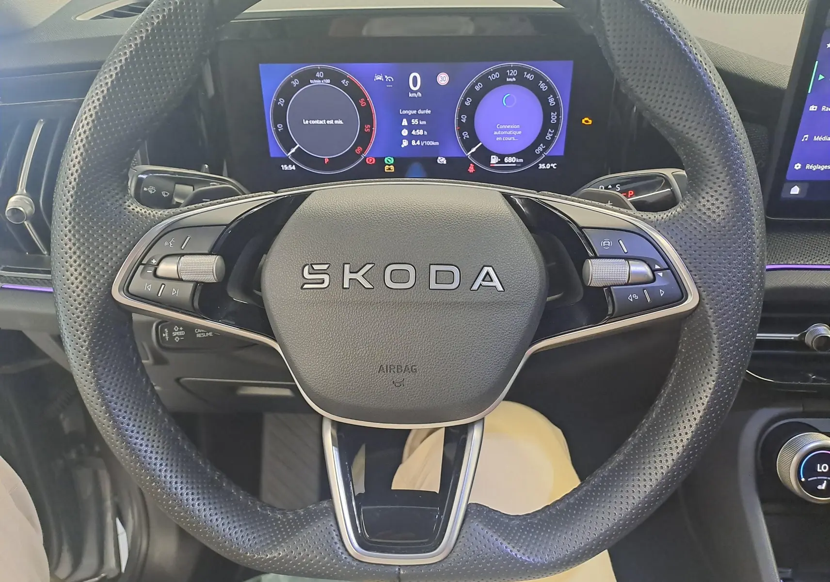 Vue intérieure centrée sur le volant perforé SKODA avec tableau de bord numérique du KODIAQ gris graphite 2025.