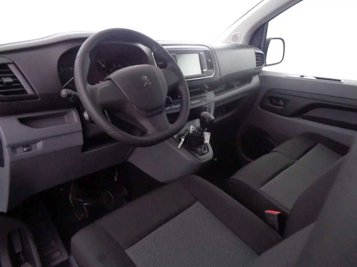 Vue intérieure côté conducteur du Peugeot Expert Fourgon 2022, tableau de bord et sièges noirs en tissu gris.