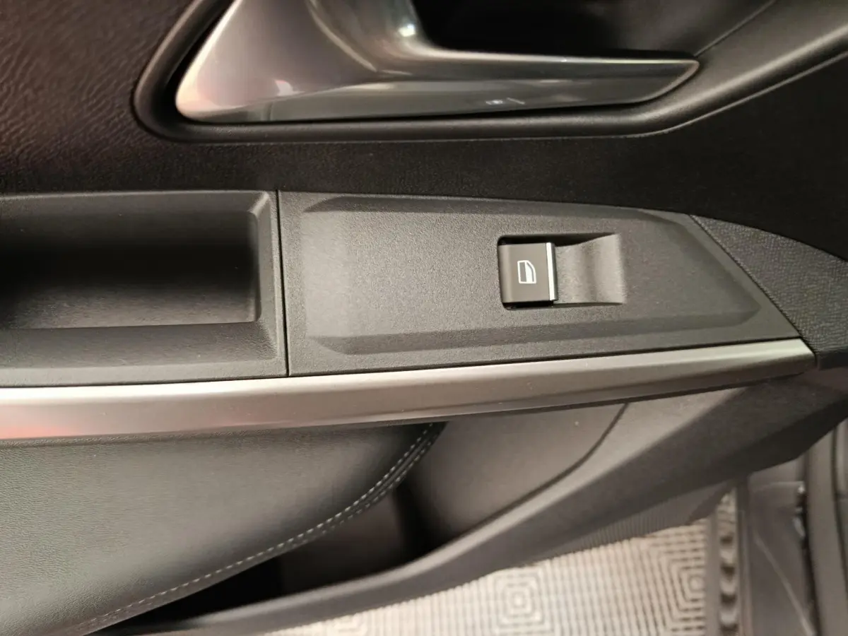 Détail de la garniture intérieure côté droit du Peugeot 3008 gris foncé, avec coutures blanches apparentes et insert métal.