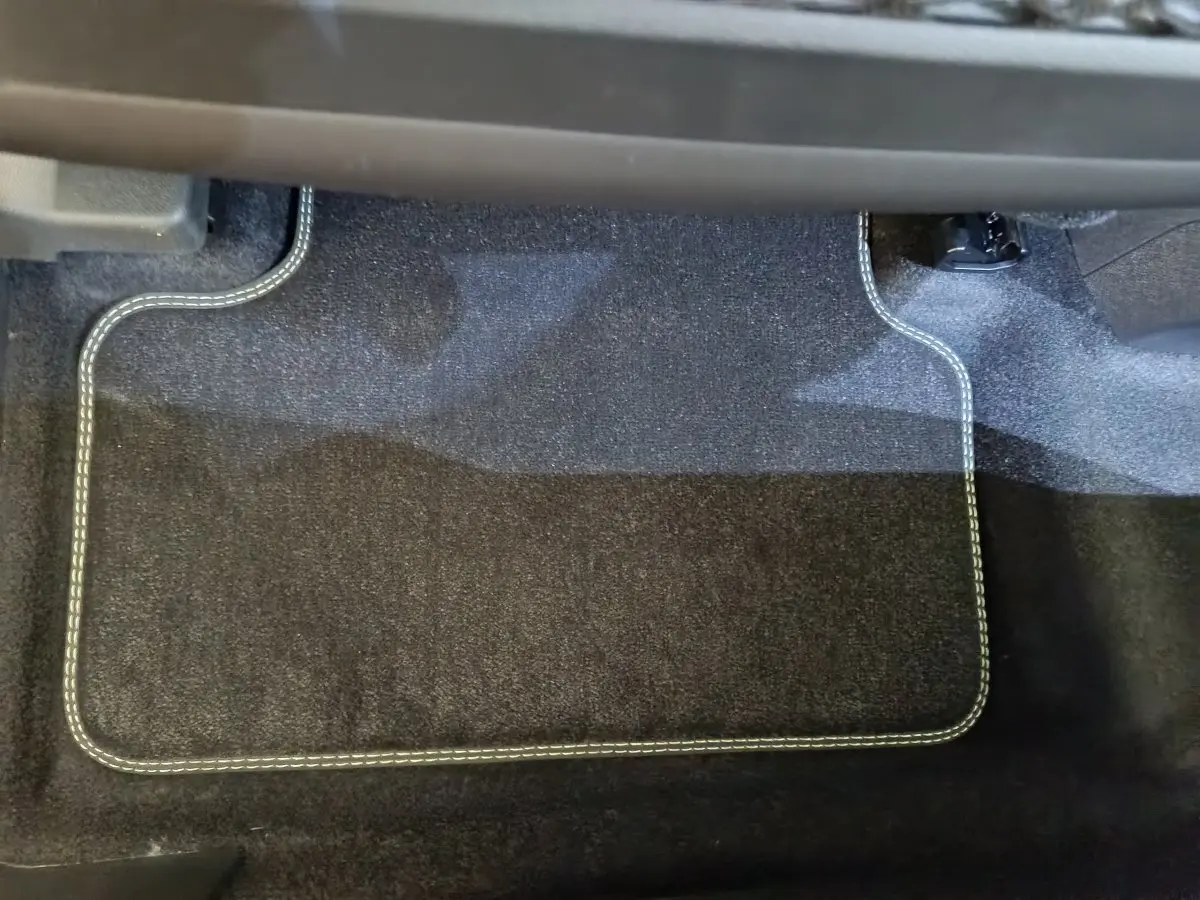 Tapis de sol noir avec surpiqûres blanches dans l'habitacle du Peugeot 3008 gris foncé 2025, côté passager.