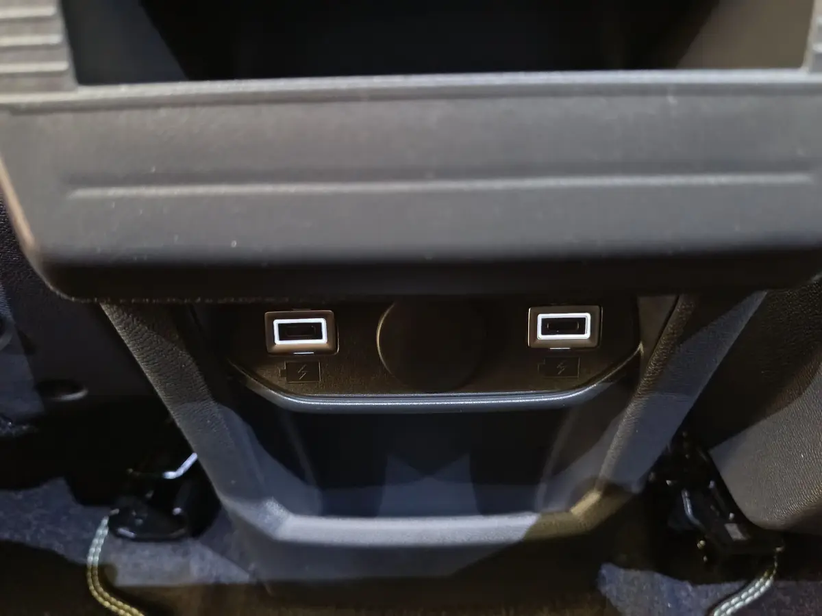 Prise USB double arrière noire du Peugeot 3008 gris foncé, version hybride 2025, vue centrée en intérieur.