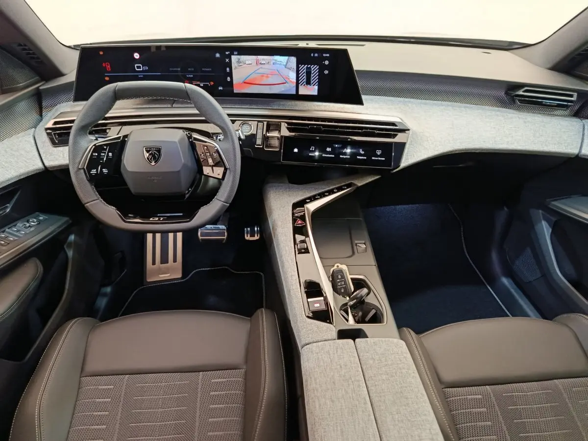 Intérieur du Peugeot 3008 1.2 Hybrid GT 2025, vue du poste de conduite avec volant cuir et grand écran tactile.