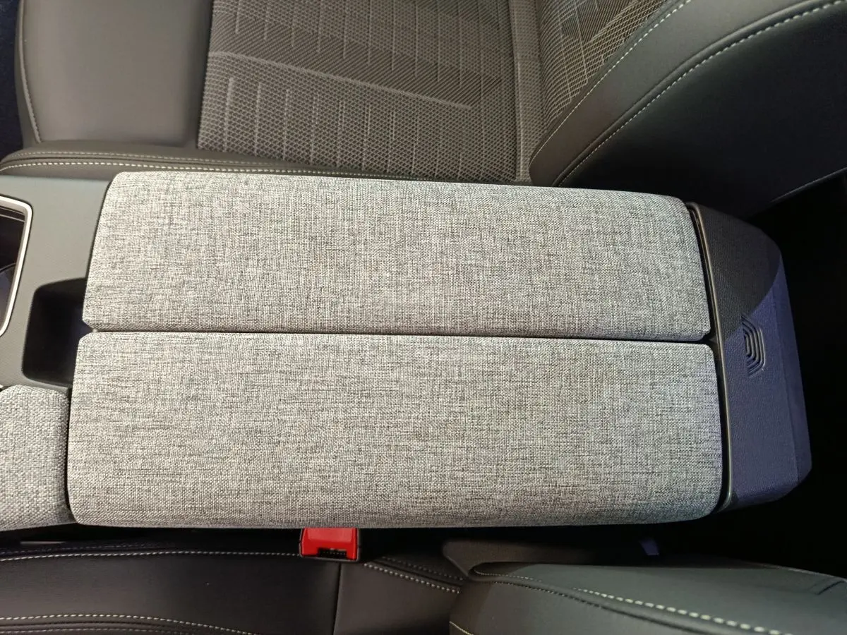 Détail de l'accoudoir central gris clair en tissu et cuir dans l'habitacle du Peugeot 3008 1.2 HYBRID 145 GT 2025.