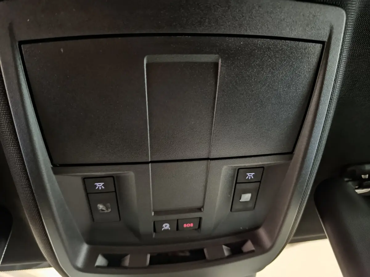 Vue rapprochée du panneau de commandes au plafond intérieur du Peugeot 3008 gris foncé, avec bouton SOS et éclairage.