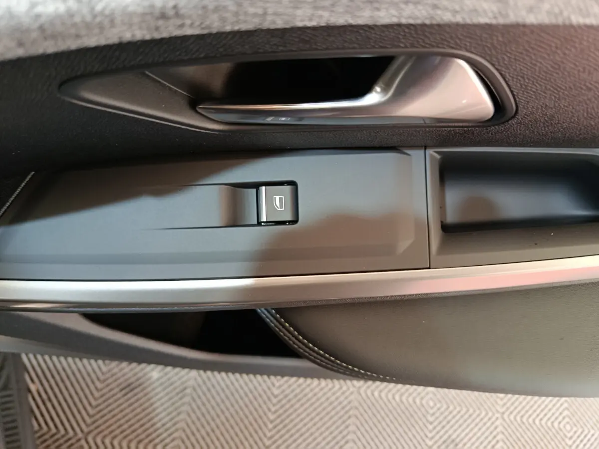 Poignée de porte intérieure côté conducteur du Peugeot 3008 gris foncé, avec bouton de commande de vitre électrique.