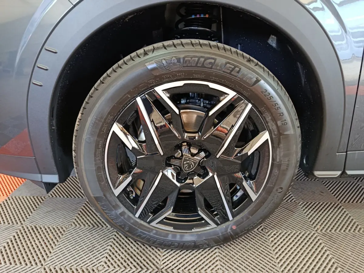 Gros plan sur la roue avant gauche du Peugeot 3008 gris foncé avec jante noire et détails chromés.